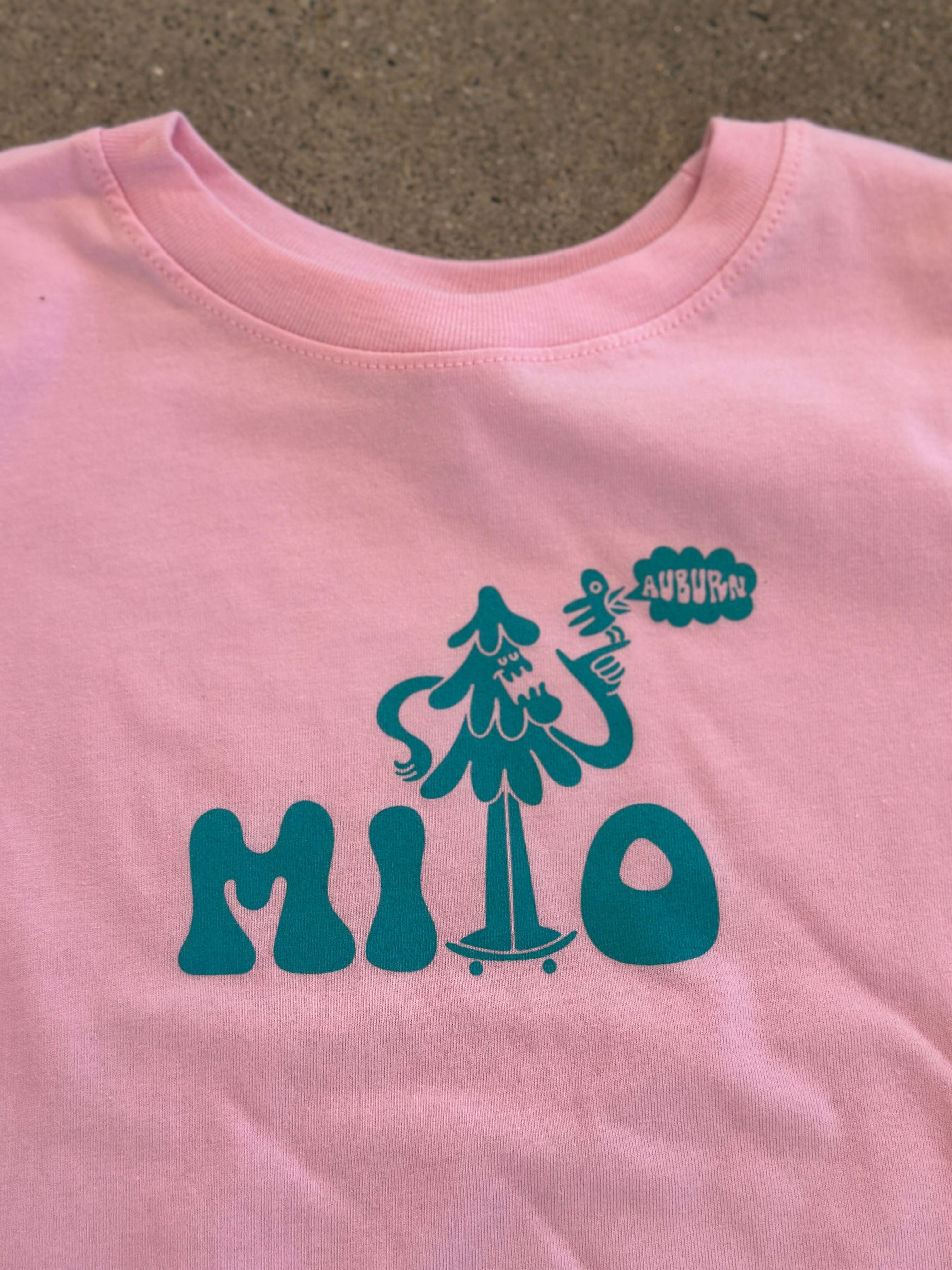 Pink sleeved shirt with teal logo and text on a textured surface